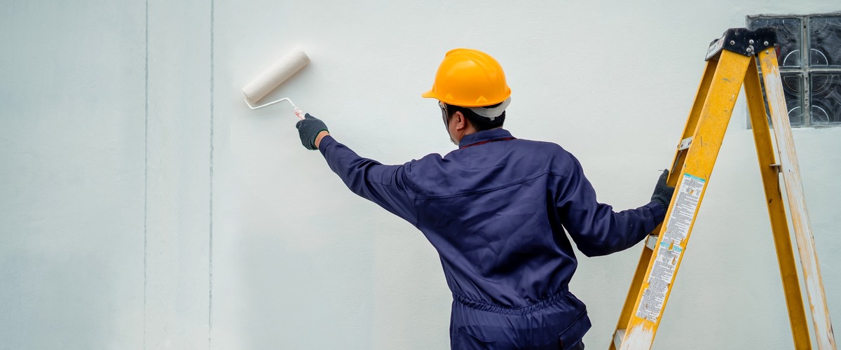 Maler streicht eine Hauswand